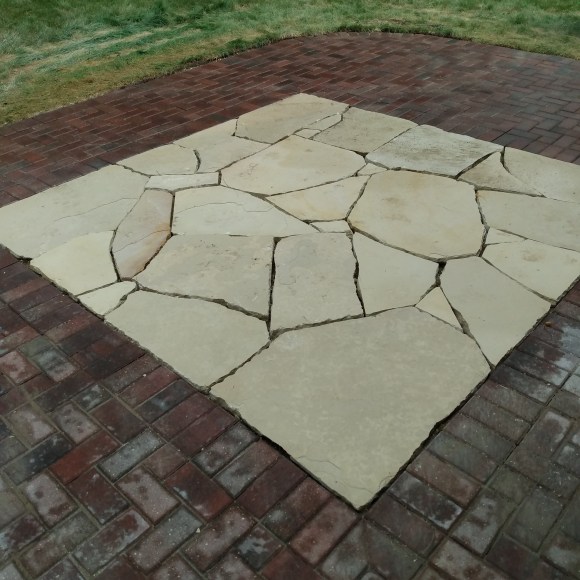 Natural stone patio surrounded by brick paver patio